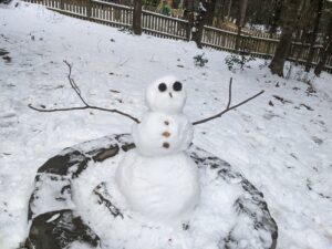 A small snowman in a fire pit surrounded by snow.